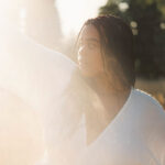 Woman wearing gauze top with sun flare in image