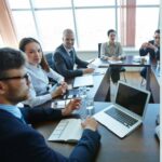 Business team in a meeting, with one employee looking thoughtful and others engaged in discussion, representing team silence at work.