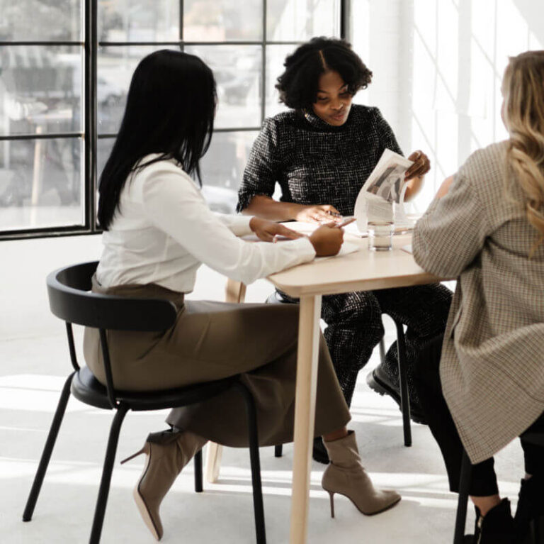 3 women sitting at table in group coaching session